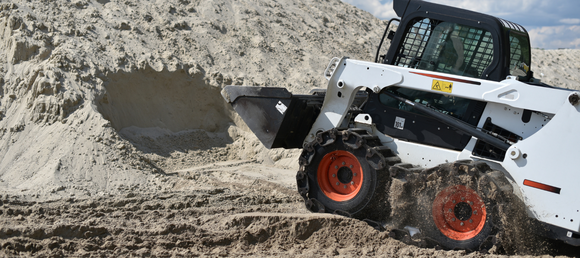 A skidsteer moving sand.