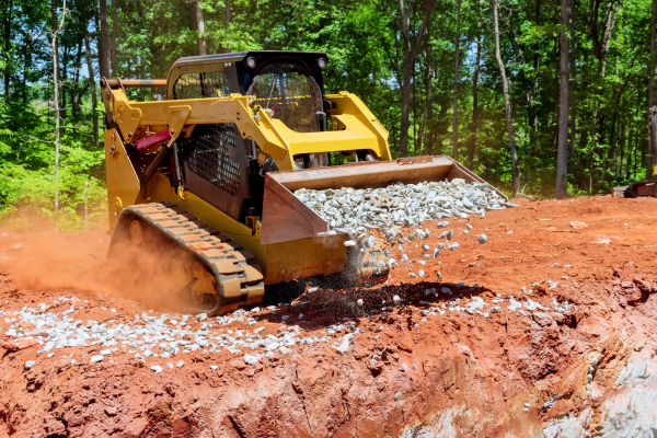 A small skidsteer carrying gravel in it's bucket.