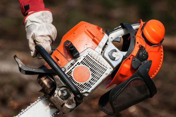 A close-up of a chainsaw being carried.
