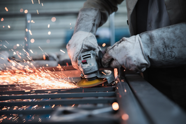 A close-up of a grinder being used and sparked shooting from the connection point between grinder and iron.